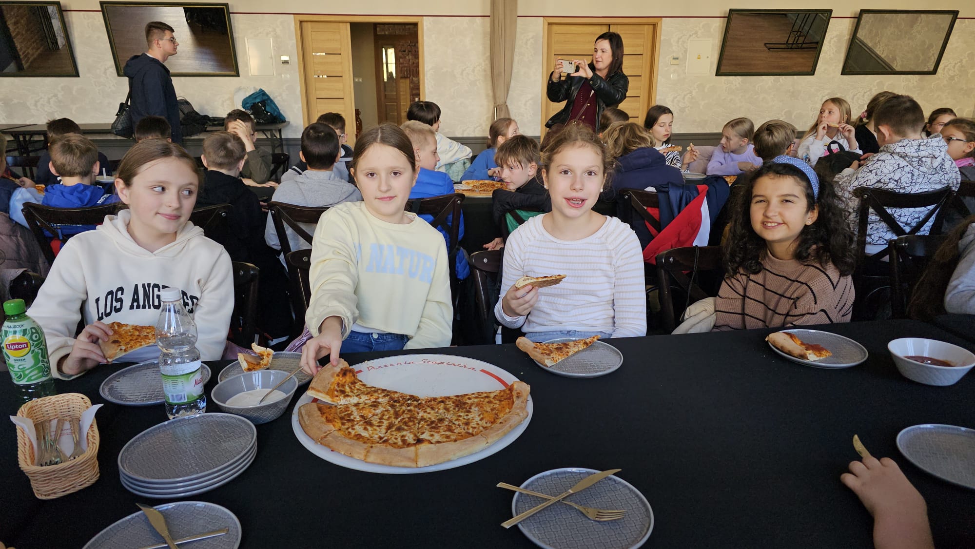 uczniowie jedzą pizzę
